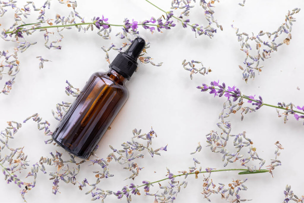 Amber bottle of lavender essential oil. Flat lay concept. Light background with water waves - Фото, зображення