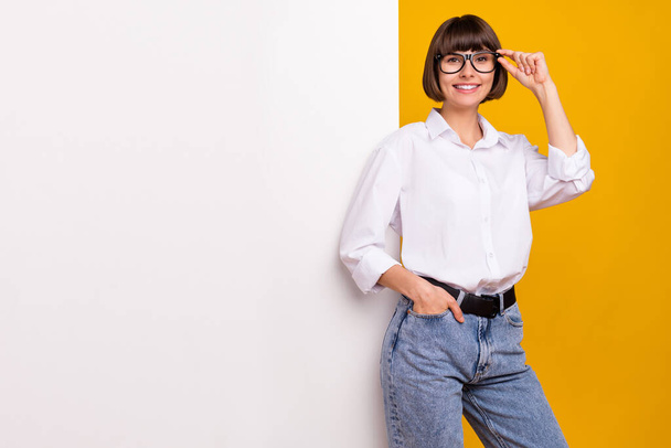 Photo of positive lady posing placard empty space wear eyeglasses white shirt isolated yellow color background. - Фото, зображення