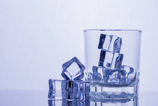 Стакан виски и льда на стеклянном столе - Фото, изображение