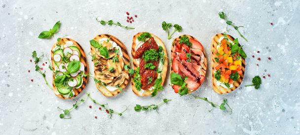 Set of homemade bruschettas and sandwiches with vegetables, cheese, mushrooms and prosciutto. Sandwich. On a stone background. - Photo, Image