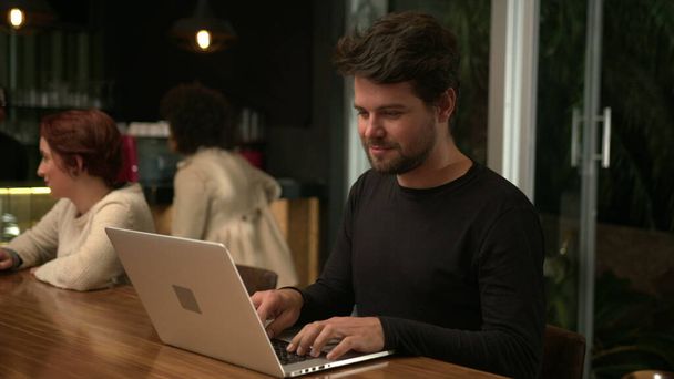 Молодий підприємець працює вночі перед ноутбуком всередині кафе. Працівник-фрілансер використовує комп'ютер у кав'ярні
 - Фото, зображення