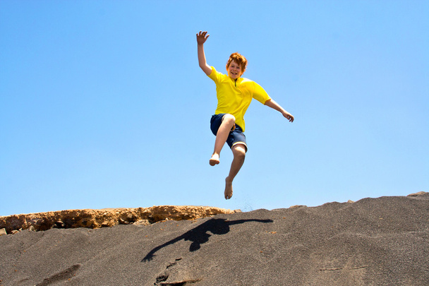 Boy has fun jumping in the dunes of the beachin the ocean - Fotó, kép