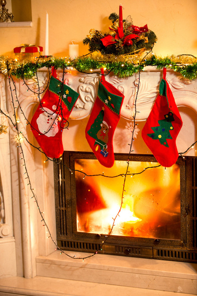 Τρεις γυναικείες κάλτσες Χριστουγέννων που κρέμονται από διακόσμησα τζάκι - Φωτογραφία, εικόνα