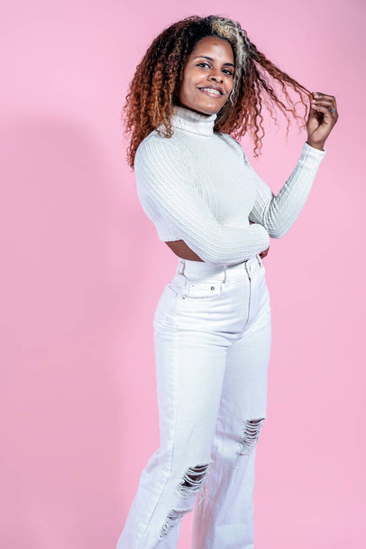 Happy black woman with curly hair smiling in studio shot against pink background. - Foto, Imagen