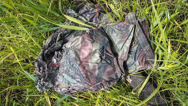 The war in Ukraine, burnt soldier's pants lie in the grass - Фото, изображение