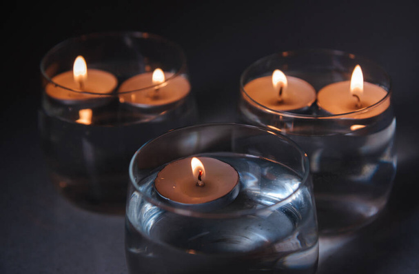 lit candles on water in candlesticks - Foto, imagen