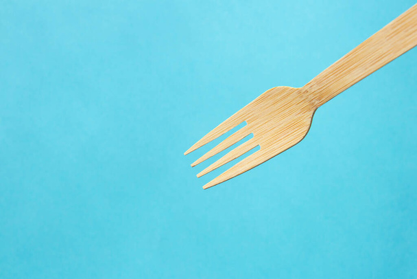 Wooden eco bamboo cutlery fork on bright blue background - Foto, Imagen