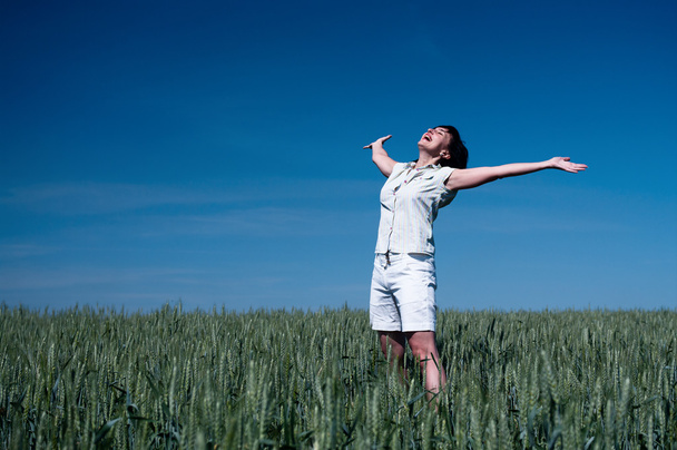 Mujer feliz en el campo de trigo
 - Foto, Imagen