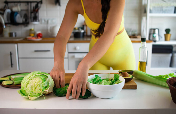 sports woman cooking healthy green salad in new kitchen - 写真・画像