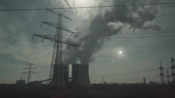 Tema da ecologia e poluição atmosférica de fábricas e usinas térmicas na Alemanha. Vista da janela do trem dos tubos de chaminé de uma planta na Baviera em tempo ensolarado. Fumaça de usina de carvão - Filmagem, Vídeo