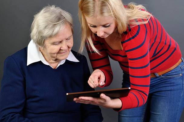 Young woman learns older woman how to use tablet. - Фото, зображення