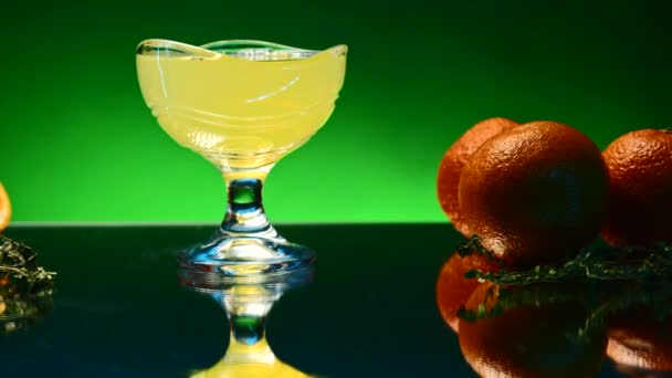 Orange alcohol cocktail in a glass on colorful wall background. Stock clip. Cold refreshing drink and a bar counter with orange fruits - Footage, Video