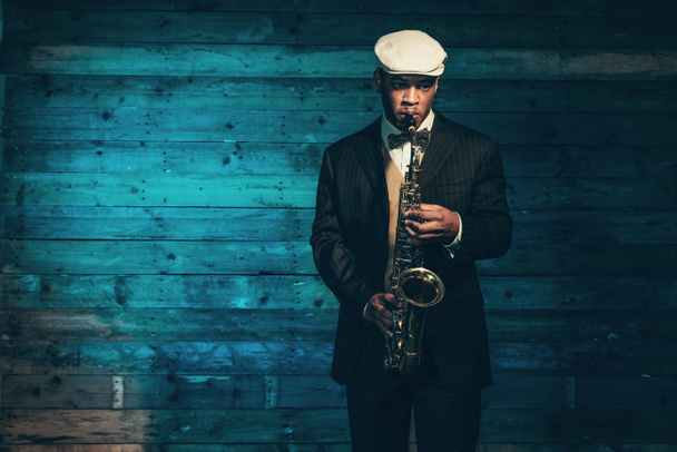 afrikanisch-amerikanischer Jazzmusiker mit Saxophon vor dem Ohr - Foto, Bild
