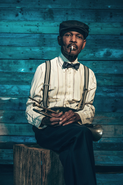 Курящий винтажный африканский старший джазовый музыкант с козырем
 - Фото, изображение