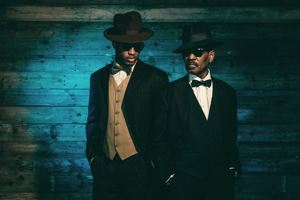 Два винтажных африканских американских гангстера перед старой деревянной ва
 - Фото, изображение