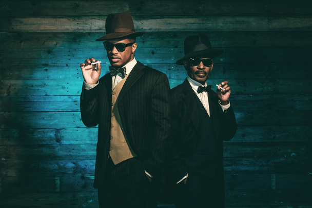 zwei afrikanisch-amerikanische Gangster rauchen Zigarette in fron - Foto, Bild