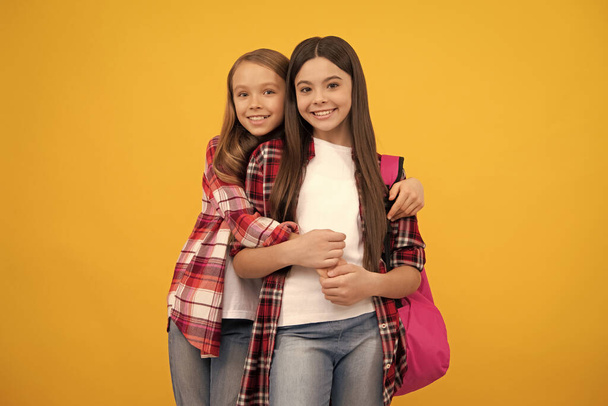 knowledge day. concept of education. kids with long hair on yellow background. september 1. happy childhood. children with school bag. happy teenager girls carry backpack. back to school. - Fotó, kép