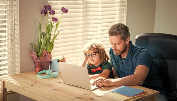 Πίσω στο σχολείο. Ο πολυάσχολος πατέρας και ο γιος με τα γυαλιά χρησιμοποιούν υπολογιστή στο σπίτι. Οικογενειακό blog. Ο σπασίκλας διαβάζει με τον δάσκαλο. μάθημα webinar βίντεο. online εκπαίδευση σε φορητό υπολογιστή. κατ 'οίκον διδασκαλία και μάθηση. - Φωτογραφία, εικόνα