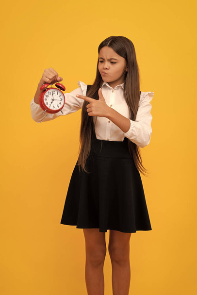 Elkéstél. Határidő. Kora reggel. A pontosság. Utolsó esély. Pontos tinilány ellenőrzi az időt. komoly gyermek ujjal mutogat az ébresztőórára. iskolás gyerek egyenruhában mutatja az időt. - Fotó, kép