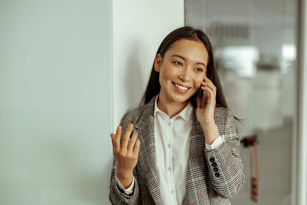 Asiatische Geschäftsfrau telefoniert und lächelt im Büro. Hochwertiges Foto - Foto, Bild