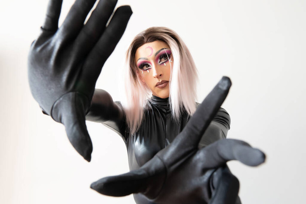 lgbtiq drag queen poseeraa kameralle mustassa lateksissa ja nahkapuvussa sivuun päin. Laadukas kuva - Valokuva, kuva