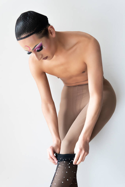 man putting on his stockings while dressing as a woman in a gender conversion, drag queen. High quality photo - Φωτογραφία, εικόνα