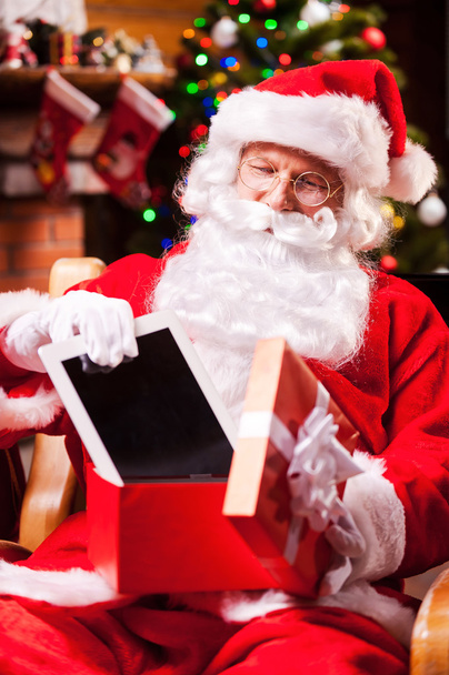 Santa Claus putting digital tablet into gift box - Foto, imagen