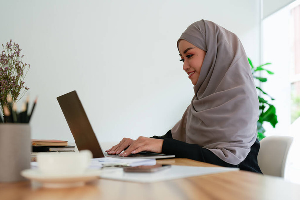 Islamische Frauen, die mit Finanzwesen arbeiten, rechnen am Taschenrechner. Junge muslimische Buchhalterin, die Berechnungen anstellt. Finanz- und Wirtschaftskonzept - Foto, Bild