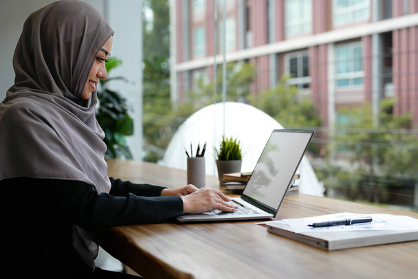 Ευτυχισμένη όμορφη μουσουλμάνα επιχειρηματίας καφέ χιτζάμπ εργάζονται για την οικονομική με την έκθεση των επιχειρήσεων σύγχρονο γραφείο. - Φωτογραφία, εικόνα