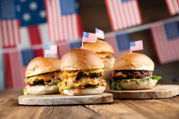 Fourth of July celebration. American flag and decorations. Burgers on rustic wooden table. - Фото, зображення