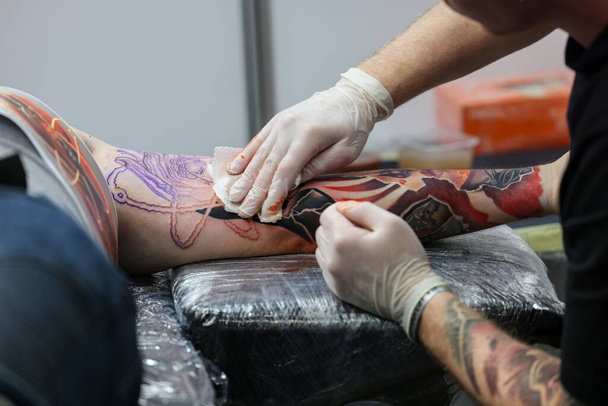 Krakova, Puola - 11. kesäkuuta 2022: 15. tatuoitu Krakovassa. Yksi arvostetuimmista tatuointifestivaaleista. Tatuoija töissä. Tatuointiprosessi. - Valokuva, kuva