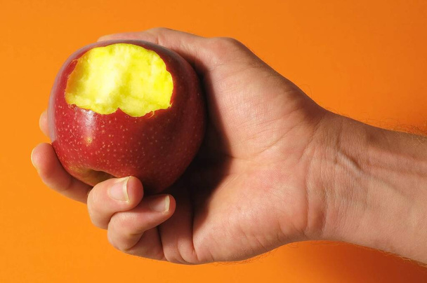 Pomme rouge piquée à la main sur un fond coloré - Photo, image