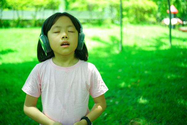 Asyalı kız sabah tatilde dinleniyor. Portakal bahçesinde müzik dinliyor. - Fotoğraf, Görsel
