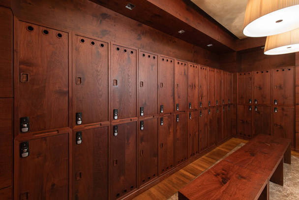 Pukuhuoneen sisätilat. Puhdas tyhjä pukuhuone iso kaapit puinen ovi ja puinen penkki - Valokuva, kuva
