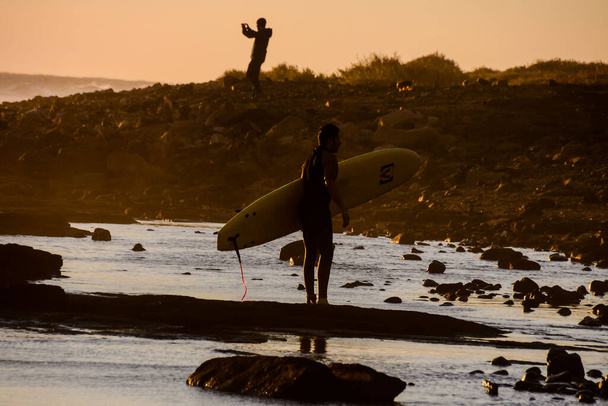 Single surfer bij zonsondergang op een rustige oceaan - Foto, afbeelding