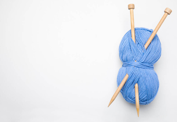 Soft light blue woolen yarn with knitting needles on white background, top view - 写真・画像