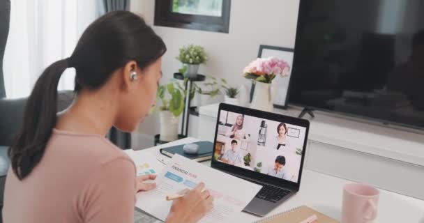 Young Asia businesswoman using laptop talk to colleagues about plan in video call meeting while work from home at living room. Self-isolation, social distancing, quarantine for coronavirus prevention. - Imágenes, Vídeo