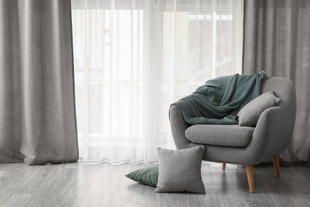 Pohodlné šedé křeslo v blízkosti útulné záclony v obývacím pokoji - Fotografie, Obrázek