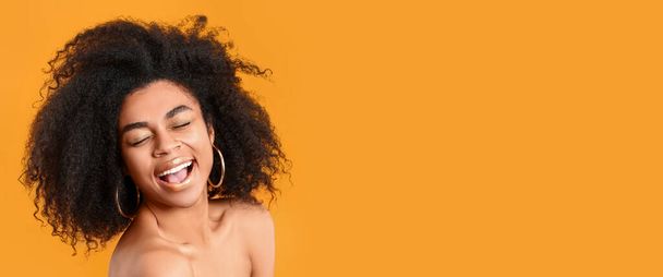 Portrét krásné šťastné afroamerické ženy se zlatými rty na oranžovém pozadí s prostorem pro text - Fotografie, Obrázek