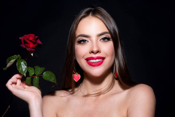 Smiling woman with naked shoulder red lips and rose flower. Fashion beauty portrait on studio black background - Foto, imagen