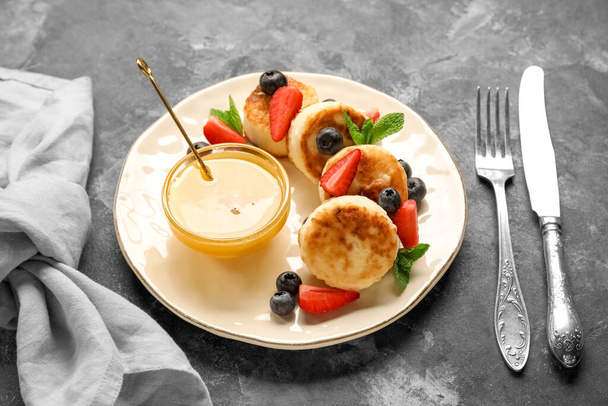 Тарелка с творогом блины, ягоды и миска с медом на темном фоне - Фото, изображение