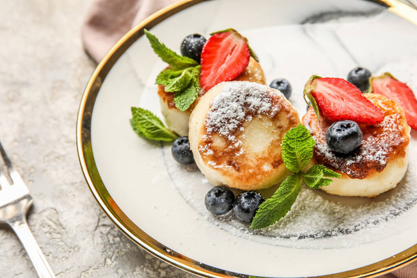 Delicious sugar powdered cottage cheese pancakes with mint leaves and berries on grunge table, closeup - Foto, imagen
