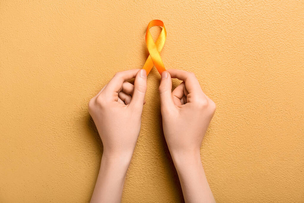 Woman with orange awareness ribbon on beige background. Kidney cancer concept - Foto, immagini