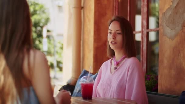 две девушки девушки наслаждаются вкусными коктейлями в кафе, проводят время в месте, образ жизни летом - Кадры, видео