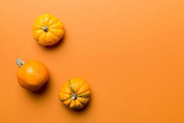 Autumn composition of little orange pumpkins on colored table background. Fall, Halloween and Thanksgiving concept. Autumn flat lay photography. Top view vith copy space. - Foto, immagini