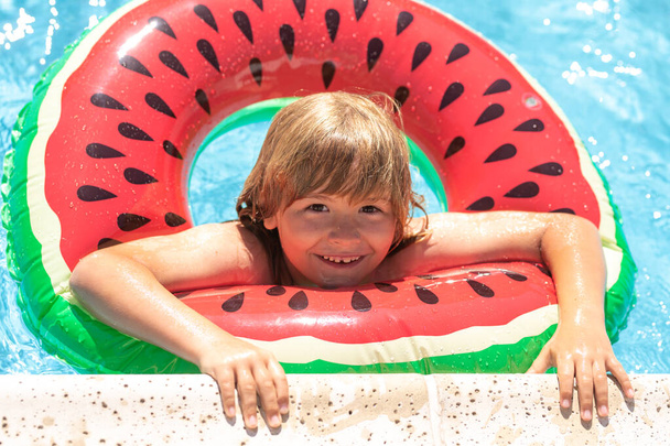 Child swimming in pool play with floating ring. Smiling cute kid in sunglasses swim with inflatable rings in pool in summer day - Foto, Bild
