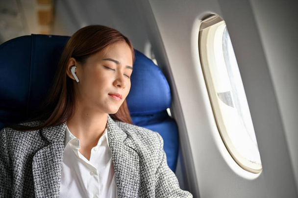 Güzel Asyalı genç iş kadını dinleniyor, kestiriyor, iş seyahati için bir yerlere uçarken uyuyor.. - Fotoğraf, Görsel