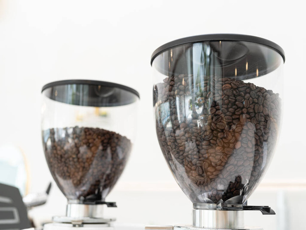 Coffee beans in machine. Close up of coffee beans in a grinder - 写真・画像
