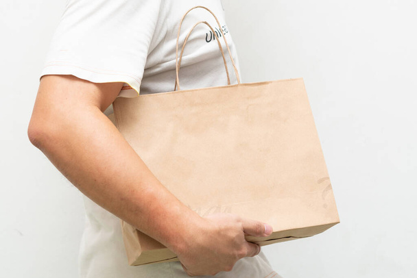Hand with Kraft paper bag isolated on white background. save the world, reduce global warming - Zdjęcie, obraz