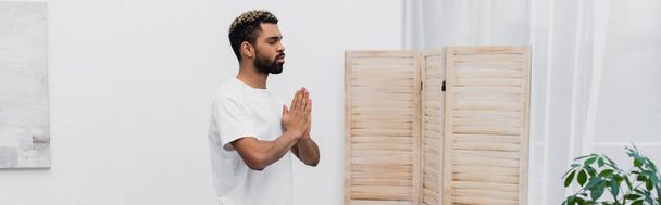 szakállas afro-amerikai férfi meditál imádkozó kezek közelében összecsukható képernyő, banner - Fotó, kép